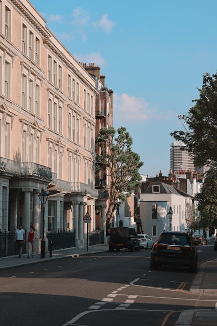 Image of a street scene at the Kentish Town Road end of tenancy, featuring a row of elegant, cream-colored residential buildings with classical architectural details and wrought-iron balconies. The st