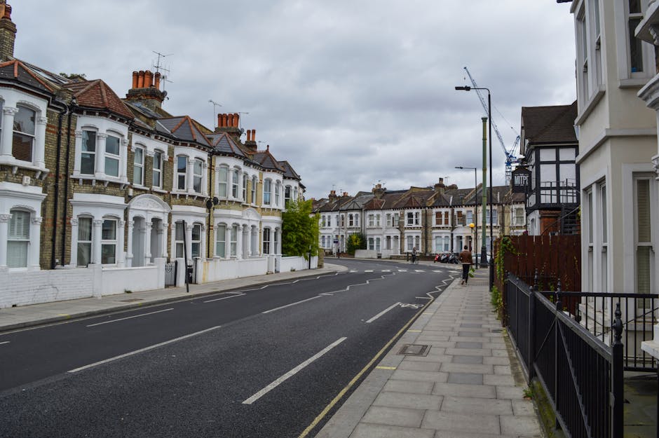 Image of a street scene at the Kentish Town Road end of tenancy, featuring a row of elegant, cream-colored residential buildings with classical architectural details and wrought-iron balconies. The st