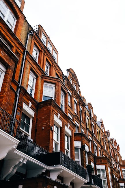 Exterior view of a row of Victorian-style terraced houses in Kentish Town, featuring decorated facades with large bay windows, some with white or light blue frames, and painted in a mix of neutral and